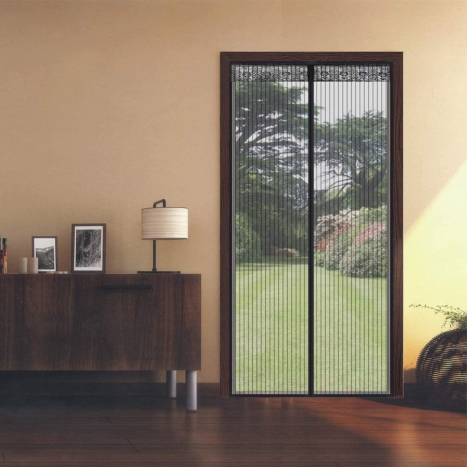Sliding glass door with decorative screen in a room with wooden furniture and a lamp.