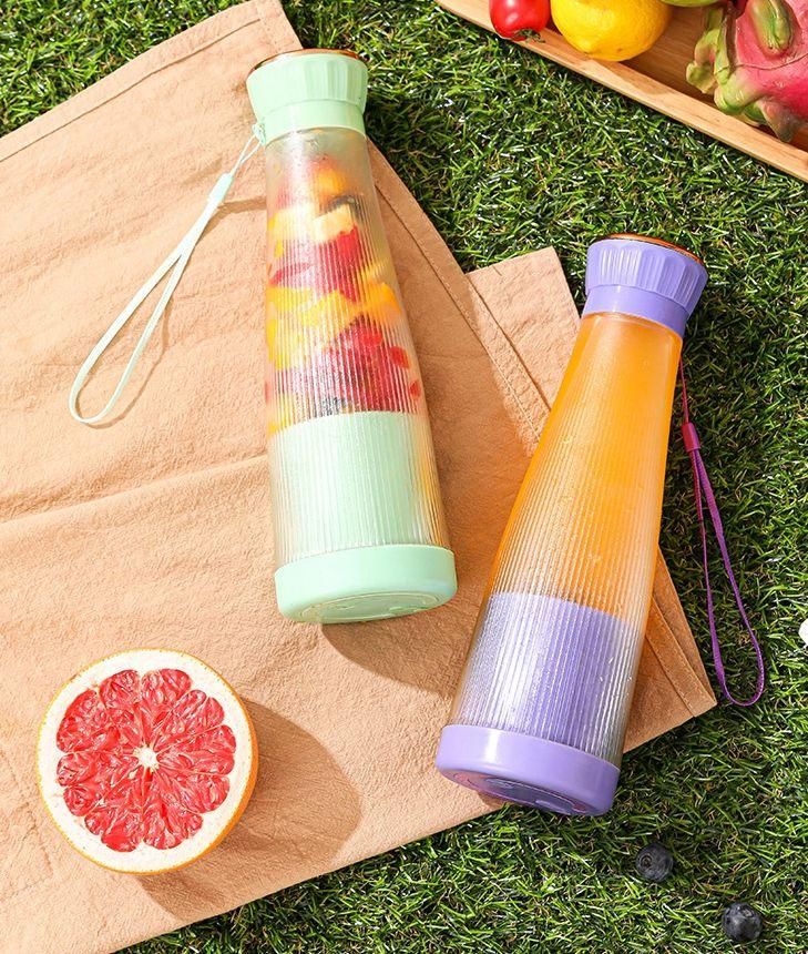 Two colorful water bottles on a grassy surface with fruits around