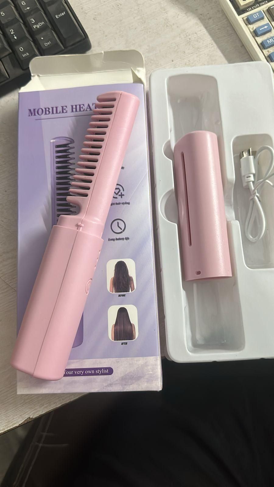 Pink hair straightener with packaging on a dark surface